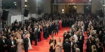 Scène de tapis rouge animée lors d'un festival de cinéma français, avec des lumières vives et une foule élégante.